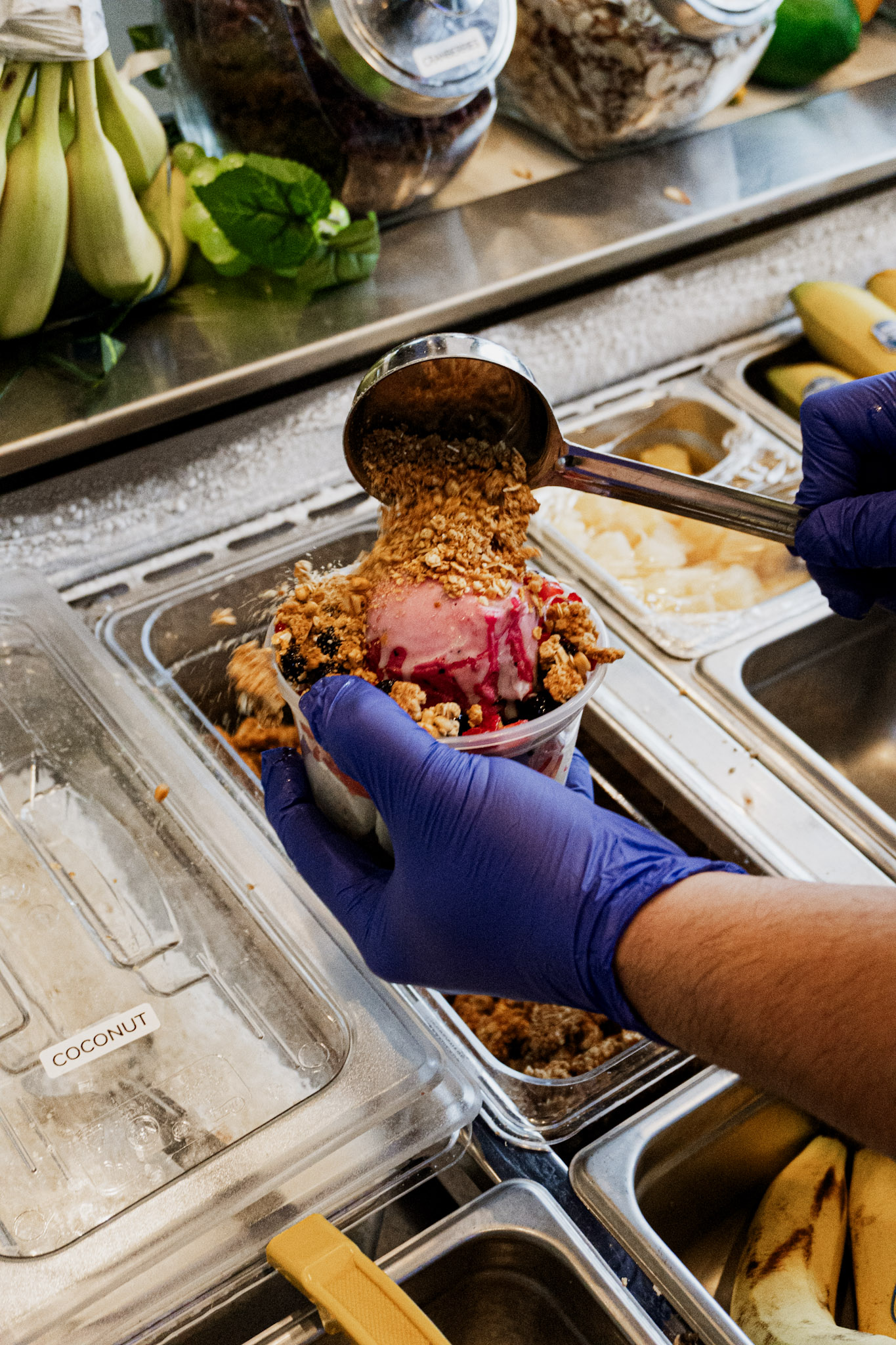 Granola being poured over a freshly prepared Okie Bowls bowl